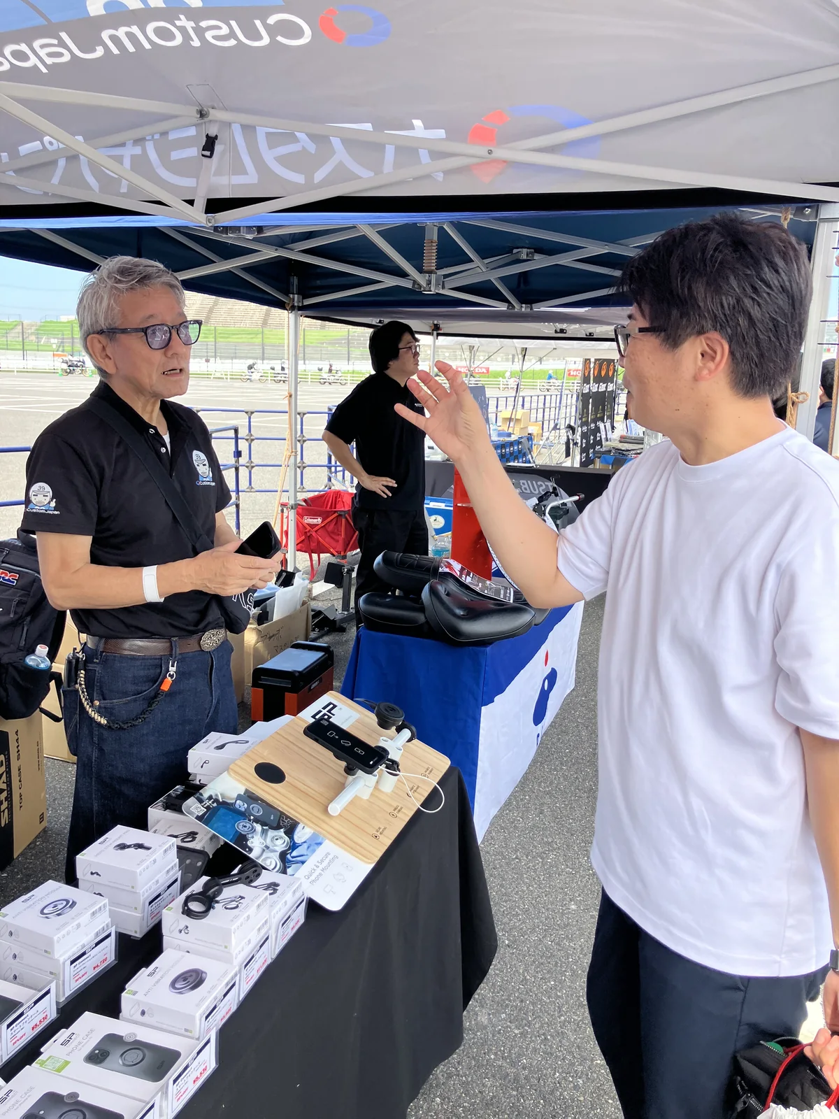 展示製品を前に来場者と話すカスタムジャパンのスタッフ